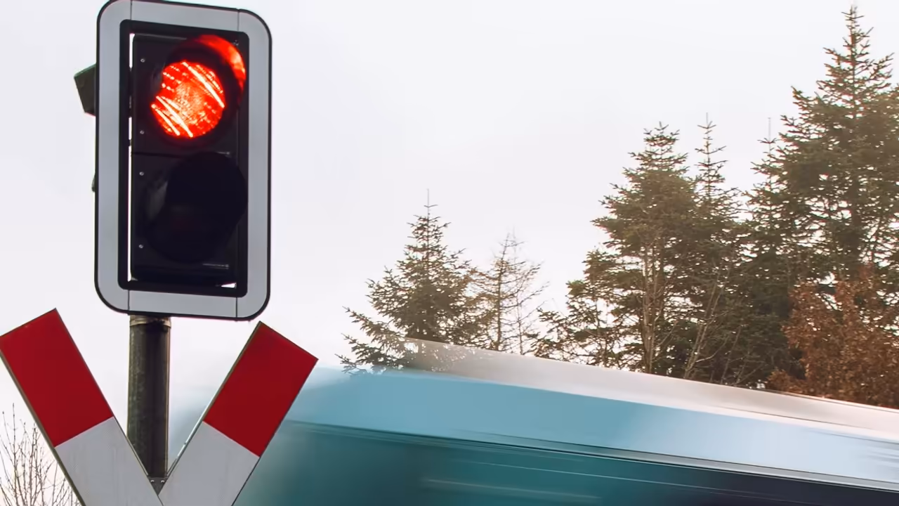 Czerwone światło ostrzegawcze i znak krzyża świętego Andrzeja przy przejeździe kolejowym